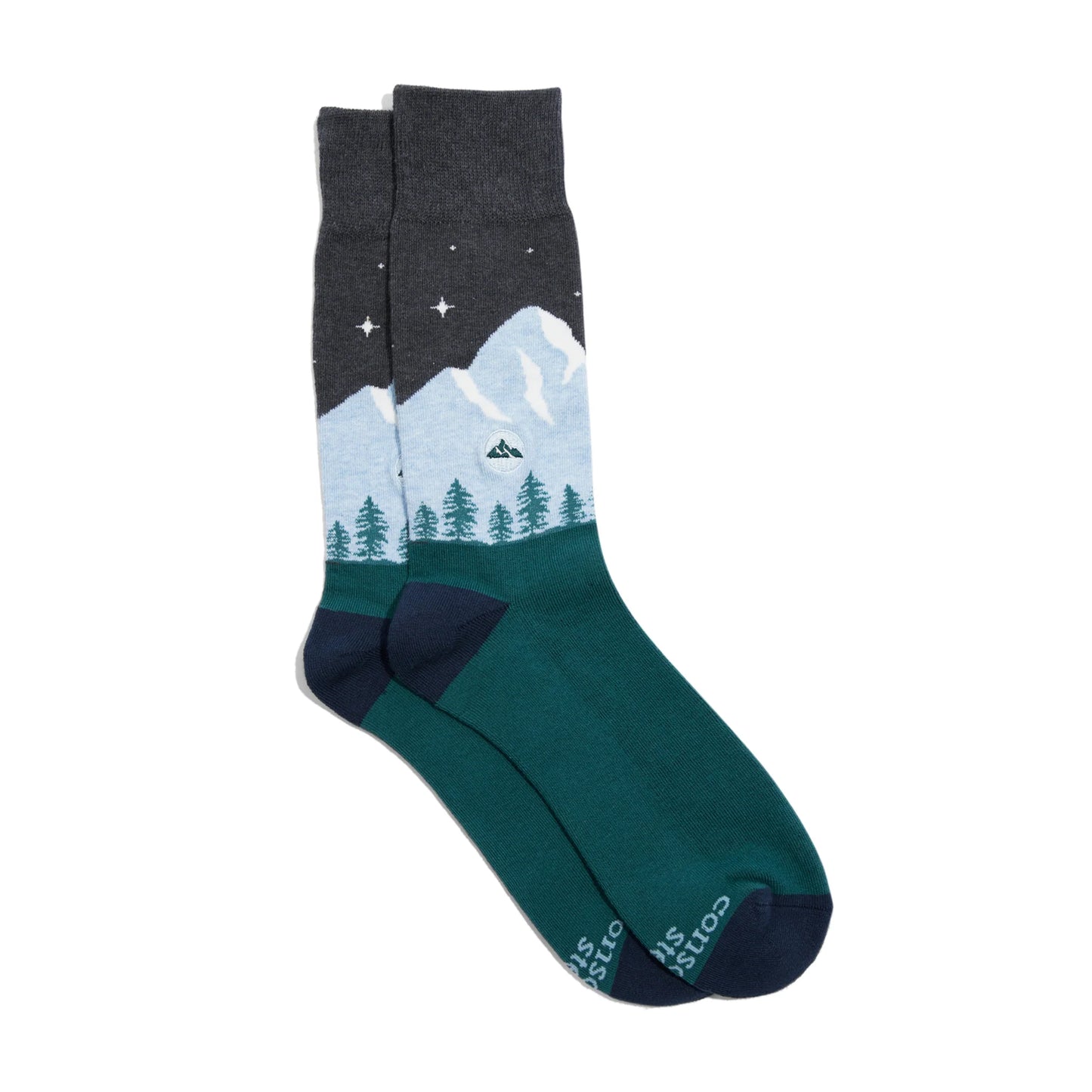A pair of socks with a light blue mountain and green trees on a dark grey background with stars.