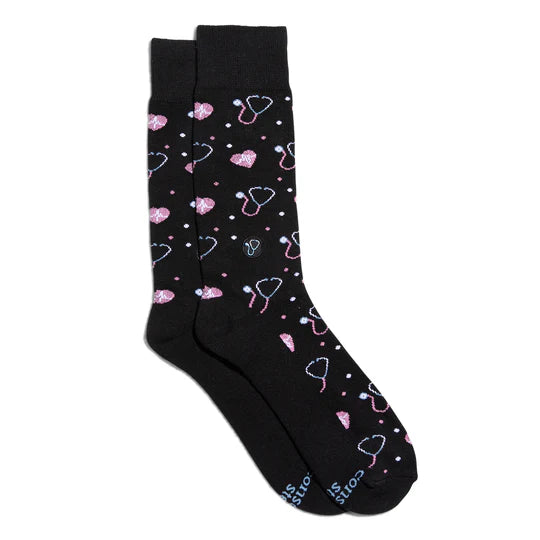 A pair of black socks with pink stethoscope patterns and small pink hearts.