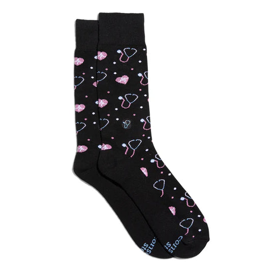 A pair of black socks with pink stethoscope patterns and small pink hearts.