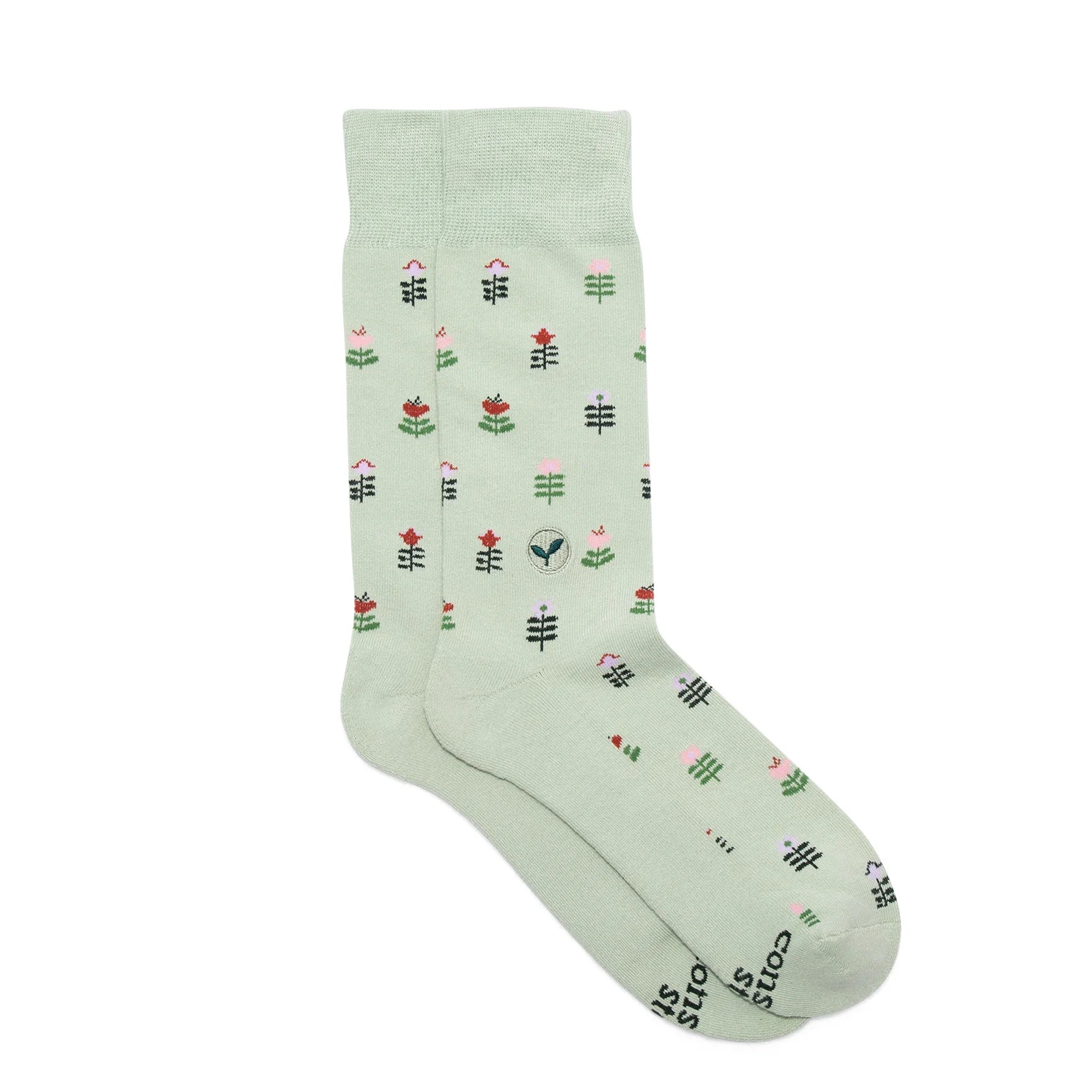 Light sage green sock with a geometric floral pattern in pink, red, and dark green laid on a white background