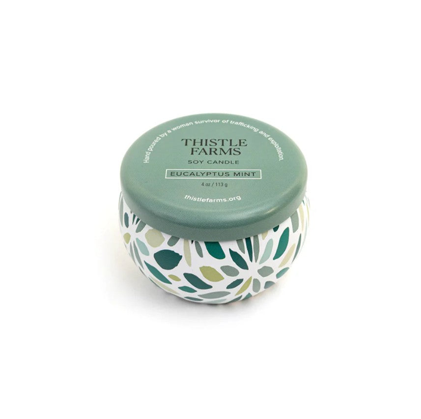 Candle jar with floral design and green lid on a white background