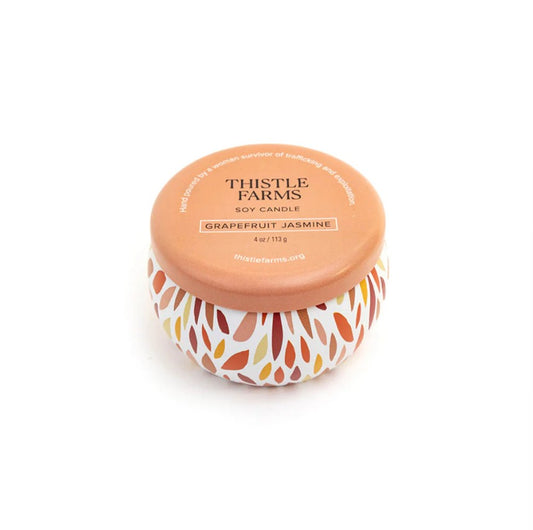 Thistle Farms soy candle with a patterned label on a white background