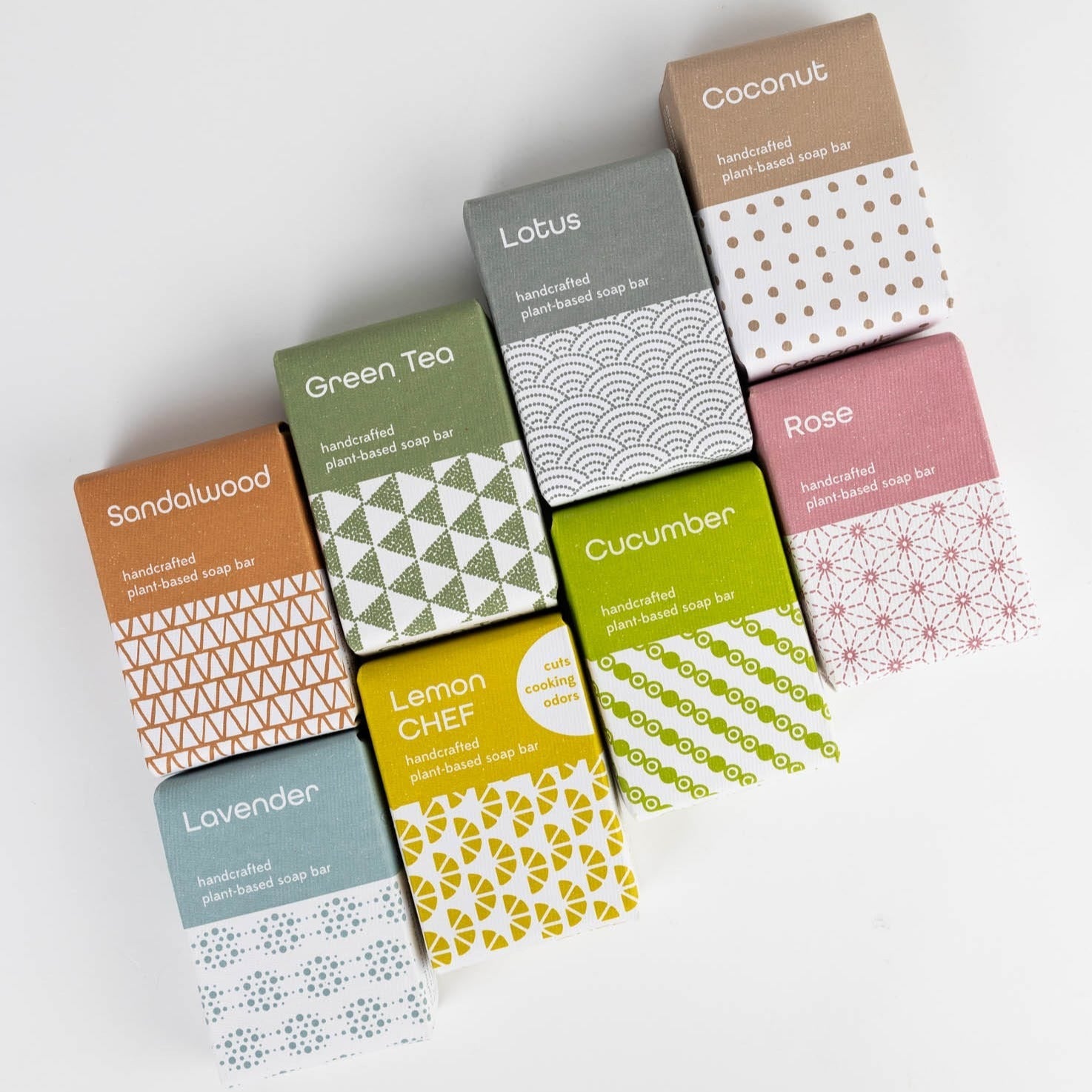 Eight bars of soap in pastel product packaging laid in an interlocking pattern on a white backdrop.