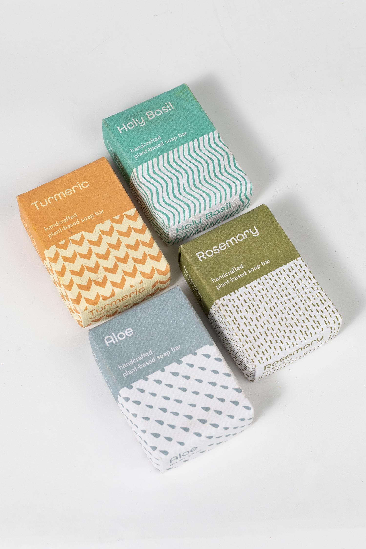 Four rectangular soap packages in different colors are laid on a white background.
