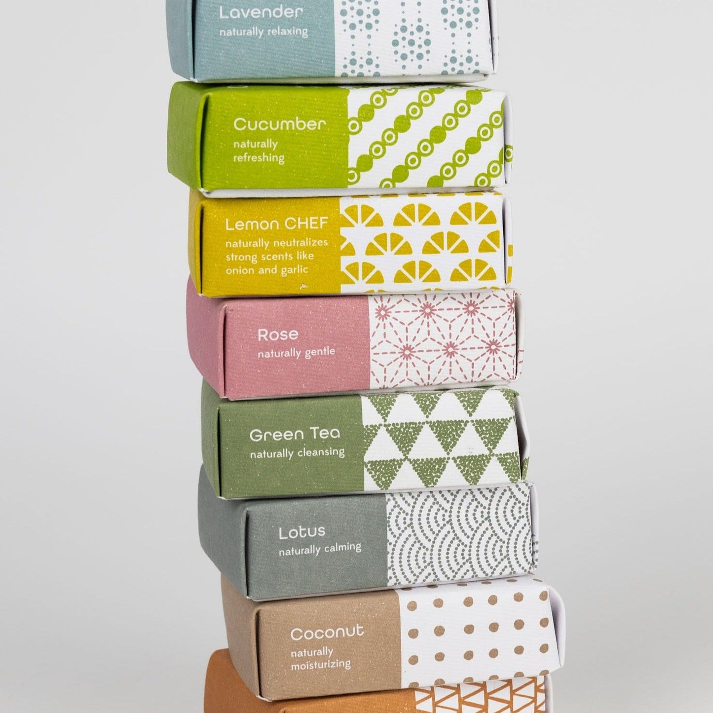 Eight bars of soap in pastel product packaging stacked in a tower.