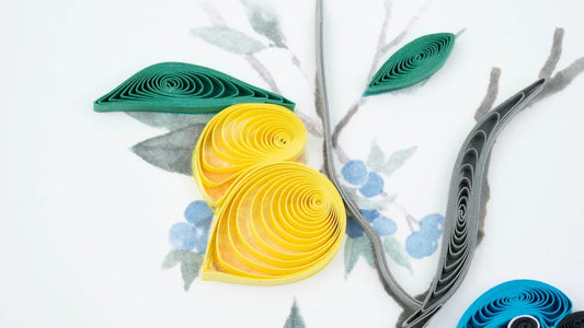 A blue and white bird sits on a branch surrounded by small lemons and blueberries.