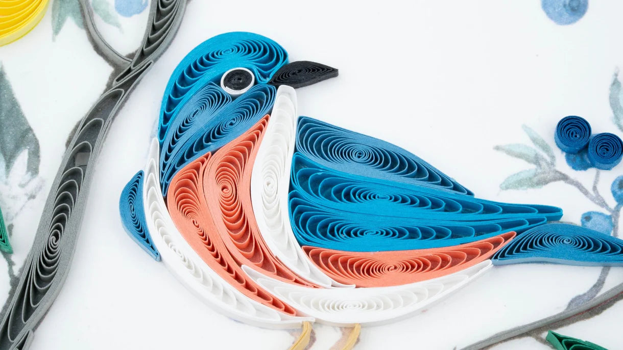 A blue and white bird sits on a branch surrounded by small lemons and blueberries.
