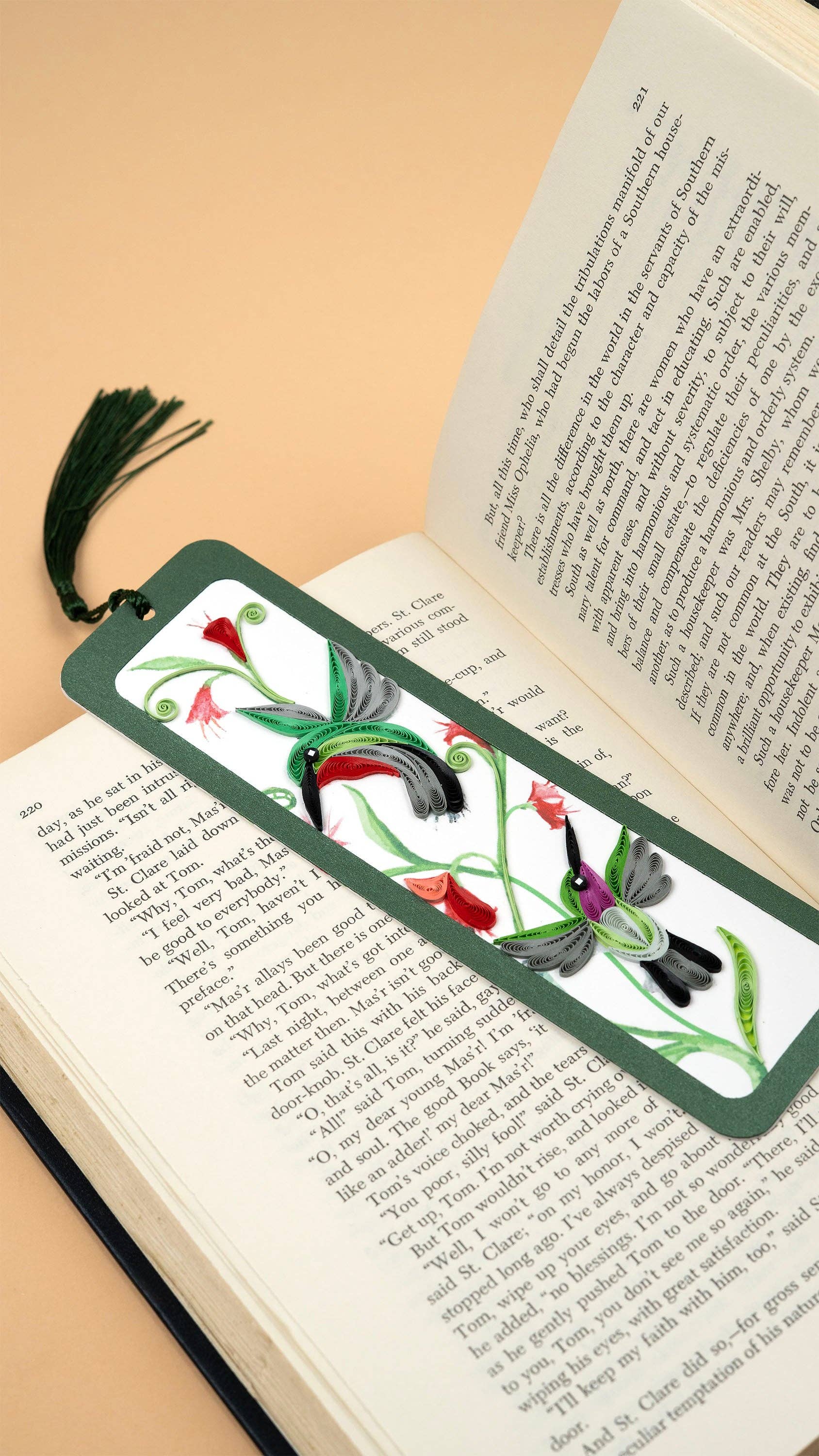 Green hummingbird bookmark rests on an open book.