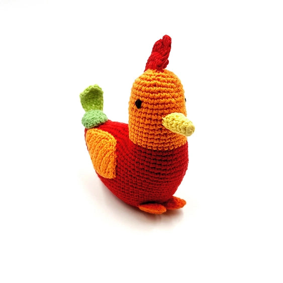 A colorful crocheted rattle in the shape of a rooster with a red body, yellow beak, and green and orange details on its head and body.