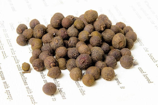 Pile of allspice berries on a white background with text