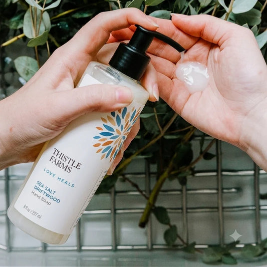 clear bottle pumping soap into hands with greenery in the background