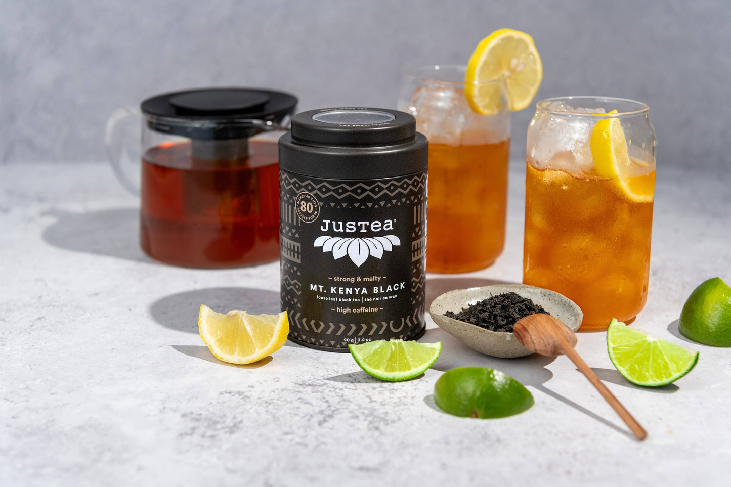 Justea Mount Kenya Black coffee jar with iced tea and lemon slices on a light surface.