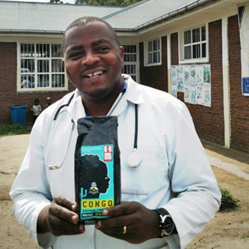 Man in a white coat holding a package of Congo Coffee Project