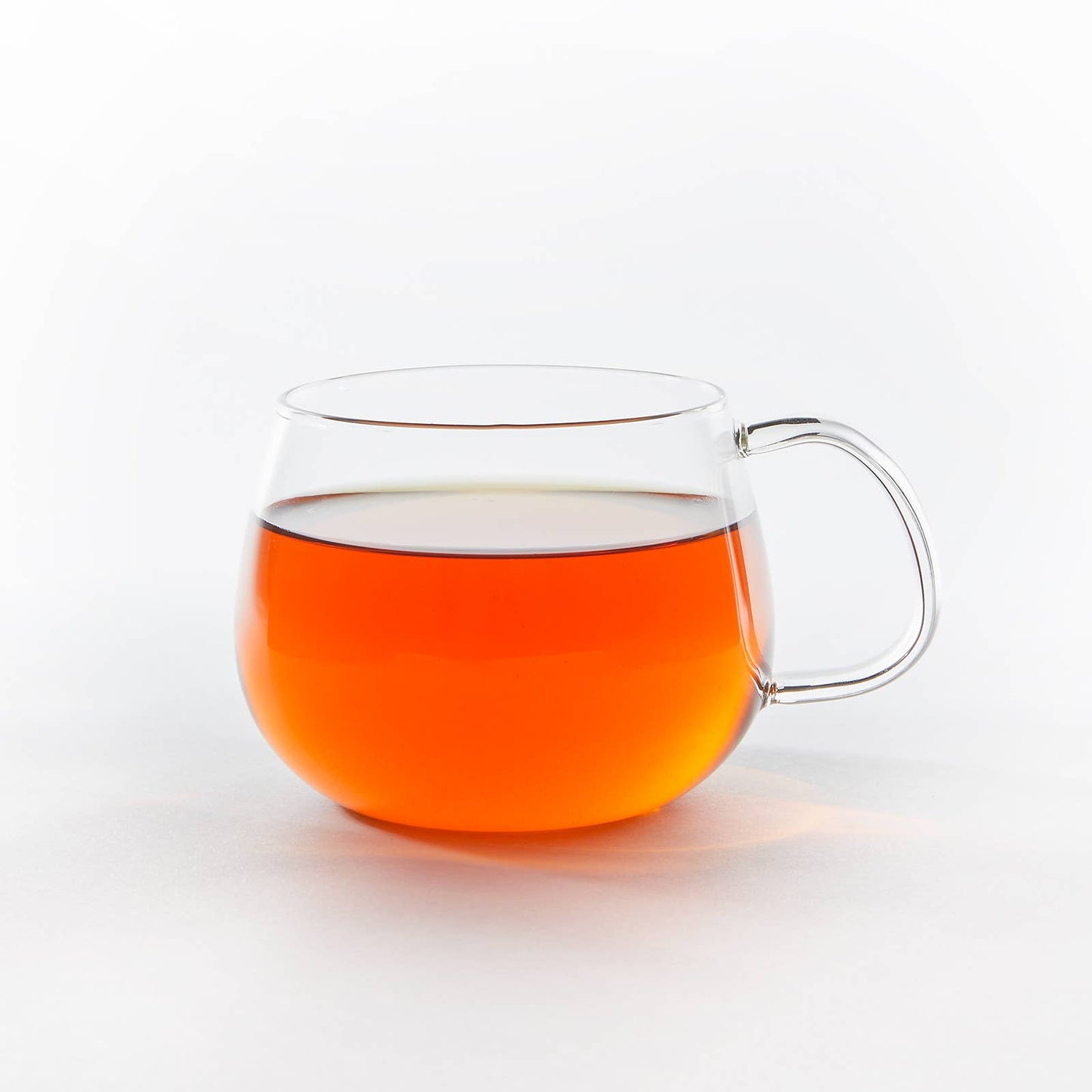 Clear glass mug filled with orange liquid on a white background