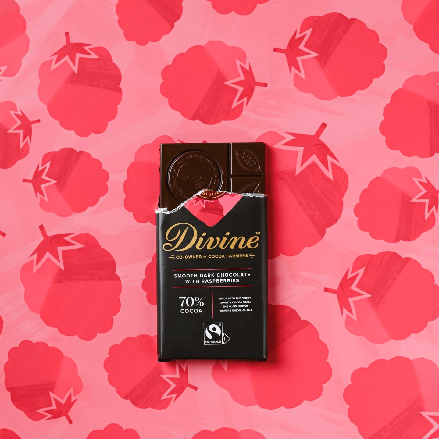 Divine dark chocolate bar packaging on a pink background with raspberry pattern