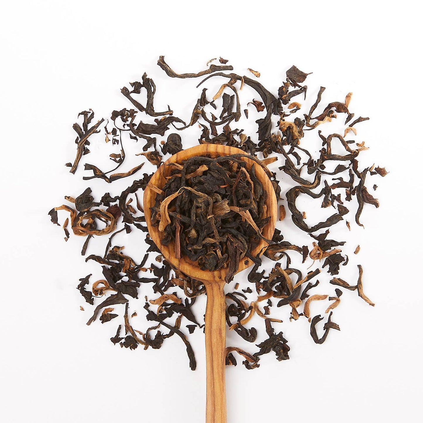 Wooden spoon filled with black tea leaves on a white background