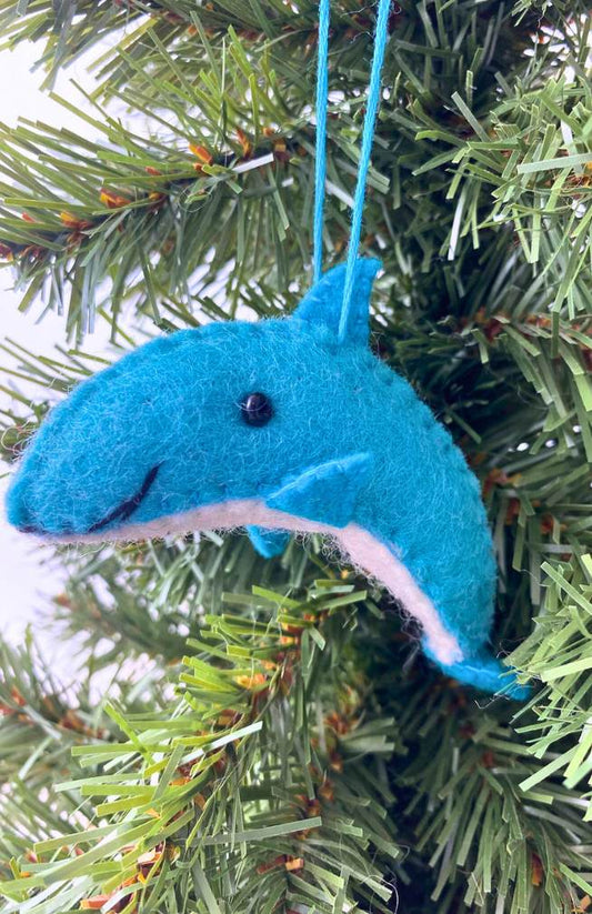A blue felt dolphin ornament with a bead eye and stitch detail, hanging on a Christmas tree.