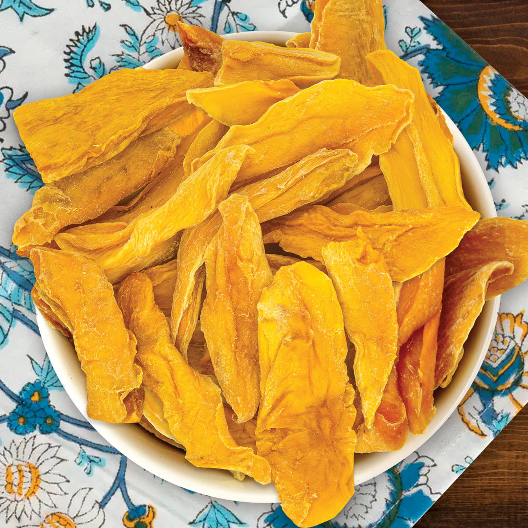 Dried mango slices in a white bowl on a patterned tablecloth