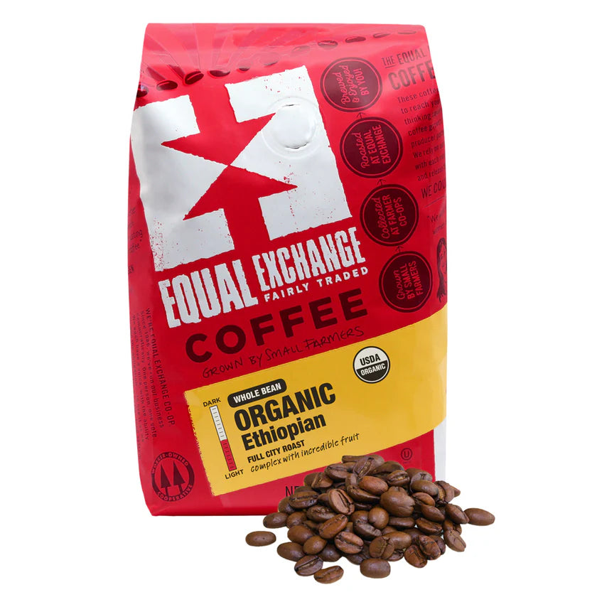 Red bag of Equal Exchange Organic Ethiopian whole bean coffee with coffee beans in front of it on a white background