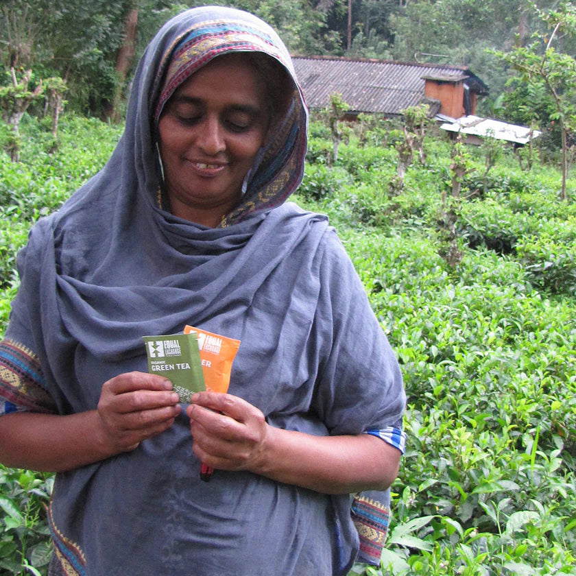 Woman holding Equal Exchange tea packages in a tea field