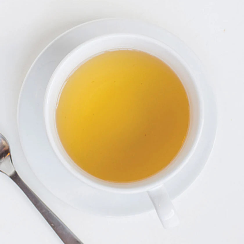 White teacup filled with tea on a white background