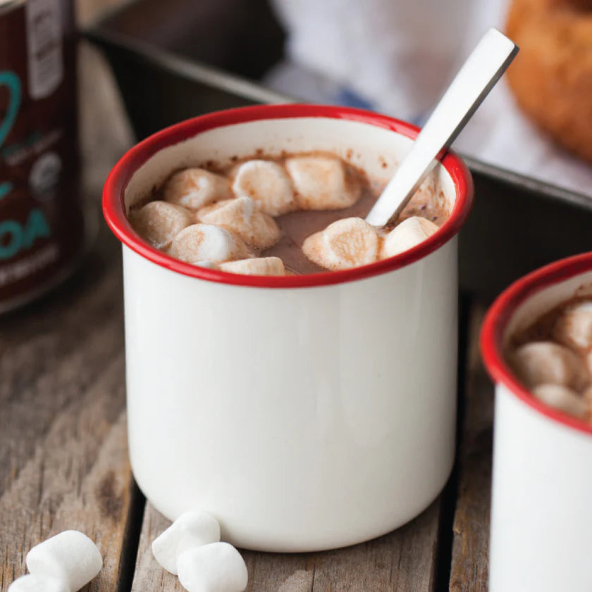 Hot chocolate with marshmallows in a white mug with red rim on a wooden surface.