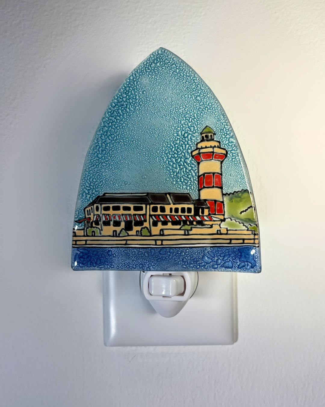 Decorative night light with a lighthouse design on a white wall.