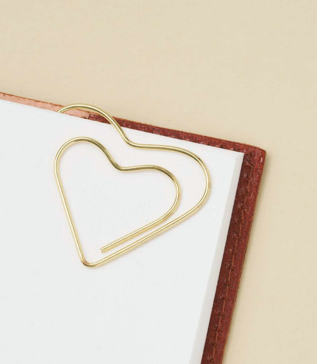 Gold wire heart-shaped bookmark attached to a page in a book