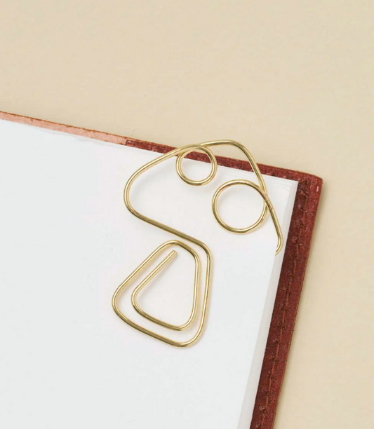 Gold wire mushroom-shaped bookmark holding a page in a book