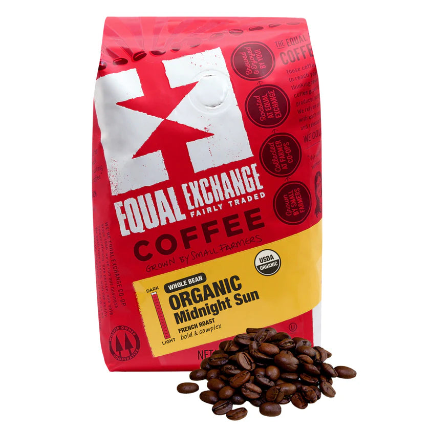 Red bag of Equal Exchange Organic Midnight Sun whole bean coffee with coffee beans in front of it on a white background