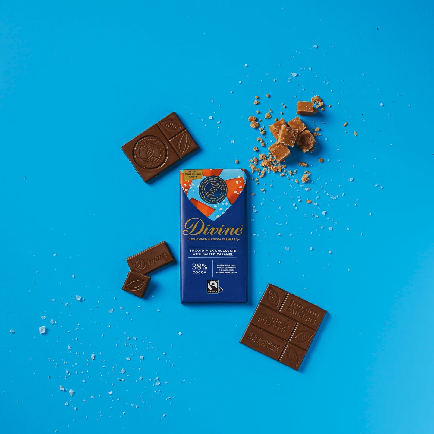 Divine milk chocolate bar with toffee and sea salt packaging on a blue background with salt and caramel