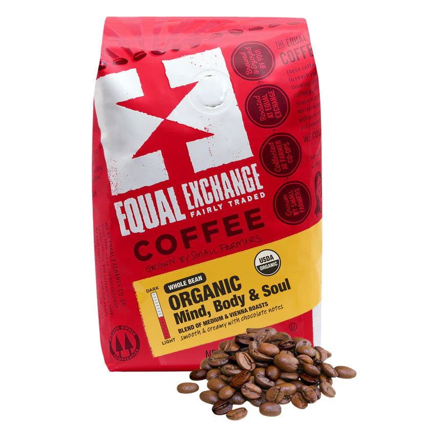 Red bag of Equal Exchange Organic Mind, Body & Soul Coffee with coffee beans on a white background