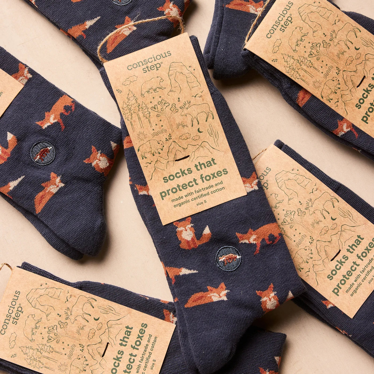 multiple pair of Navy socks with fox pattern on a tan background in tan packaging with green type
