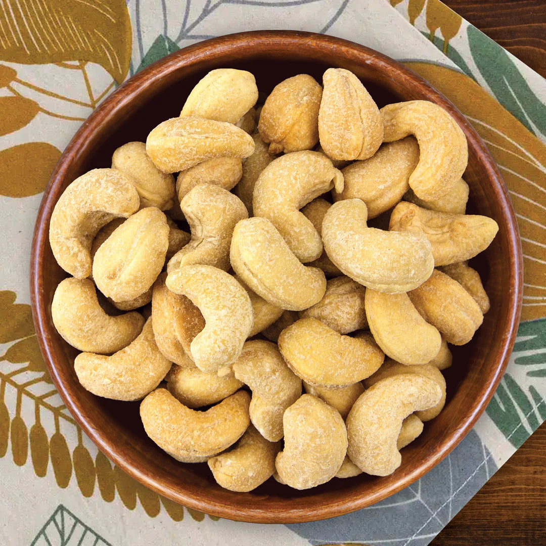 Brown bowl filled with cashews on a patterned tablecloth
