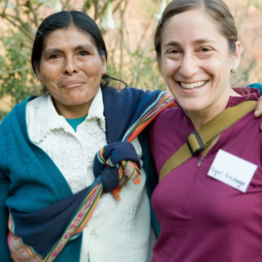 Two women standing together outdoors, one wearing a colorful shawl.