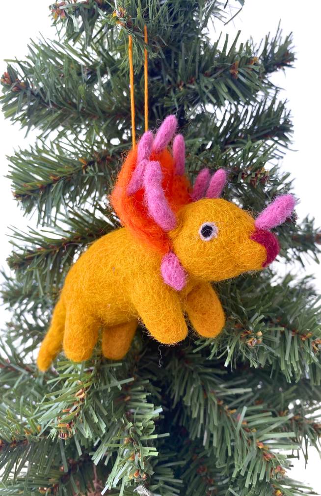 Felted rhino dinosaur ornament in gold with orange and pink, hanging on a Christmas tree.